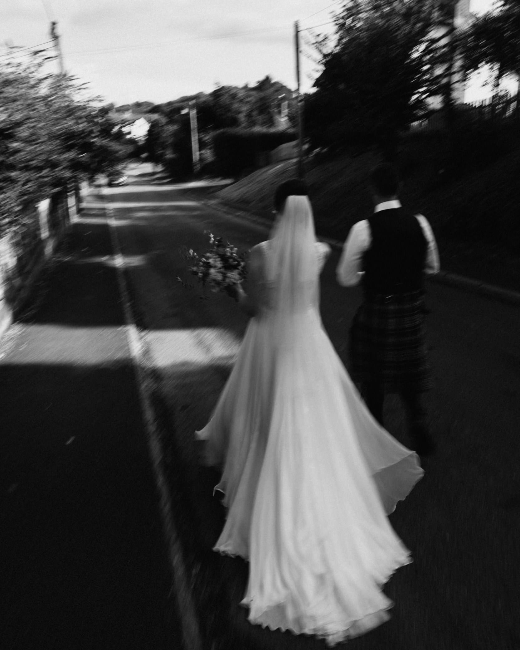 bride and groom walking down a road in Somerset