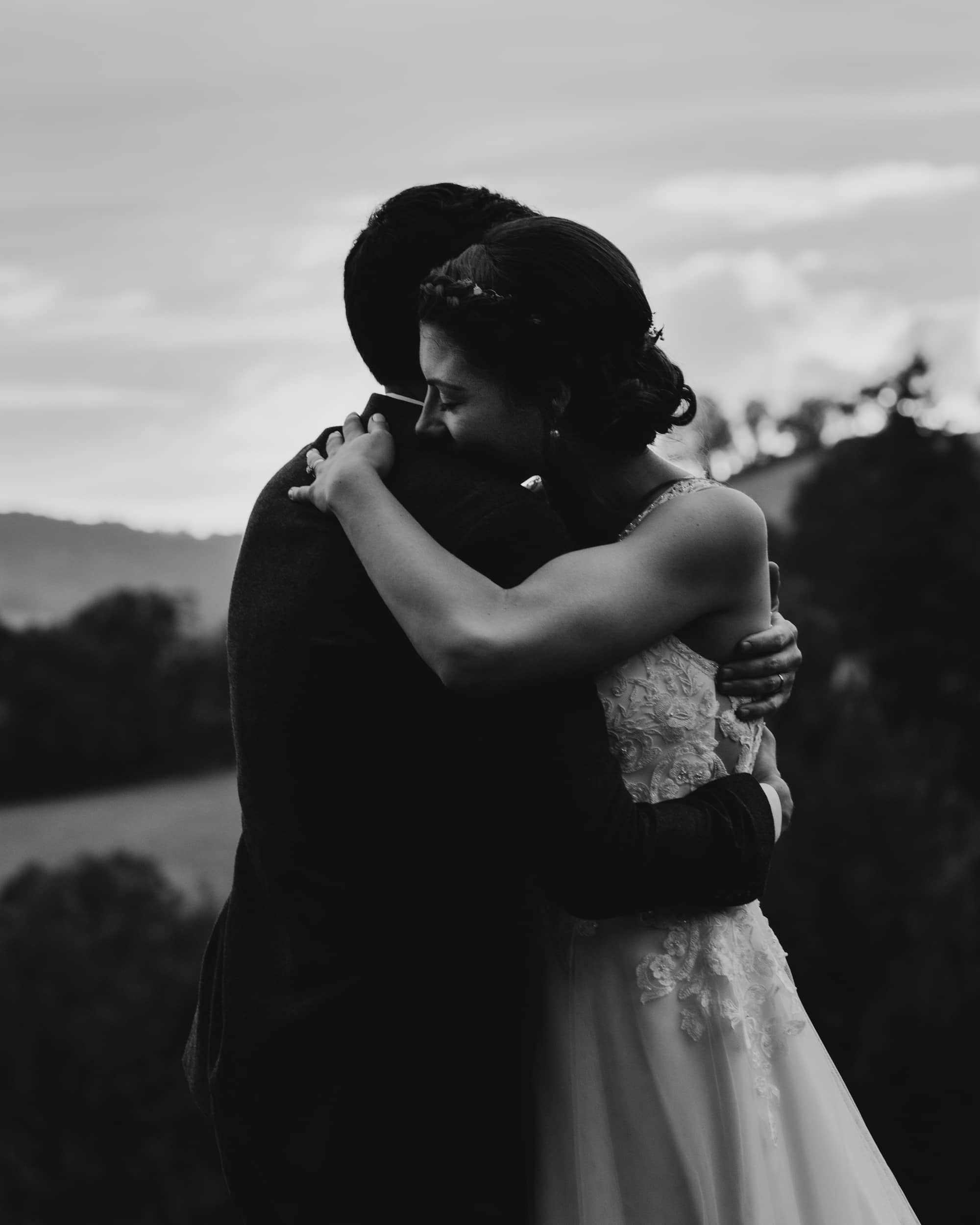 bride and groom hugging in field