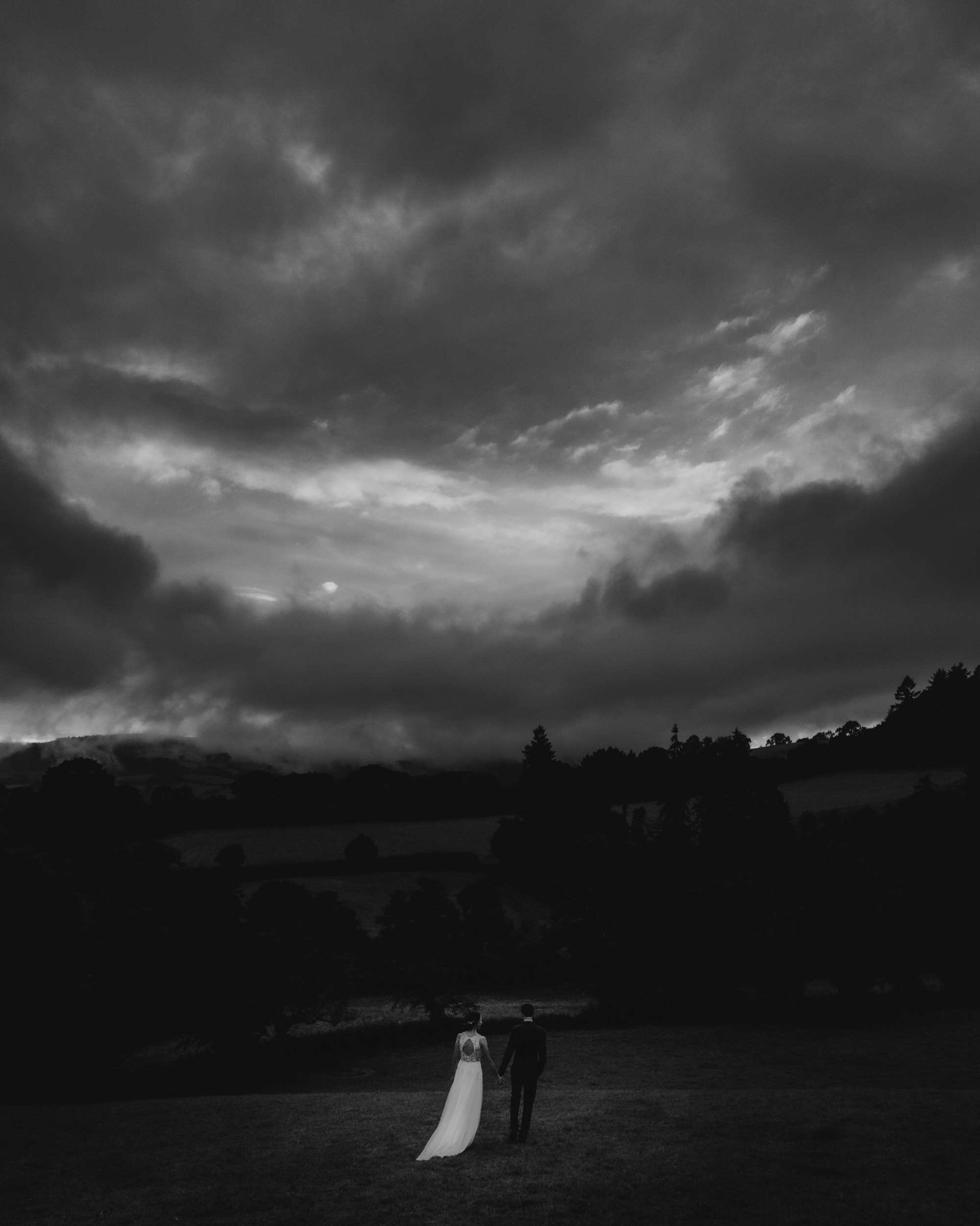 married couple standing on hill overlooking the great barn devon